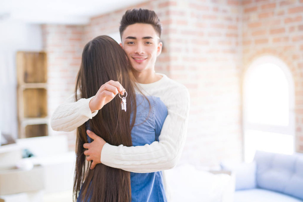 Молодая пара, держа в руках ключи от нового дома, улыбается счастливо и взволнованно переезжая в новую квартиру
 - Фото, изображение