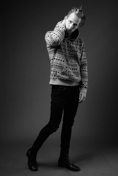 Студійний знімок молодого красивого чоловіка в светрі на сірому фоні в чорно-білому
 - Фото, зображення