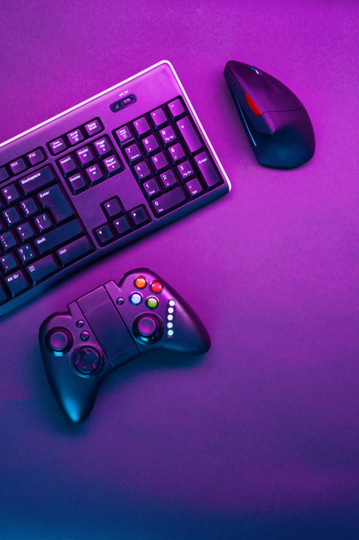 Keyboard, mouse and joystick on violet table background. - Photo, Image