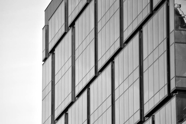 Fragment van de gevel van een modern kantoorgebouw. Buitenkant van de glazen wand met abstracte textuur. Zwart-wit. - Foto, afbeelding