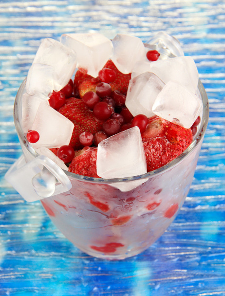 Frozen berries in bucket of ice on color background - Fotó, kép