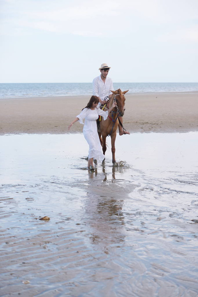 fotosessão ao ar livre de jovem asiático casal na praia com cavalo
  - Foto, Imagem