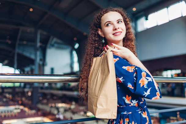 Νεαρή χαρούμενη γυναίκα κρατώντας χαρτοσακούλες για ψώνια στο εμπορικό κέντρο. - Φωτογραφία, εικόνα