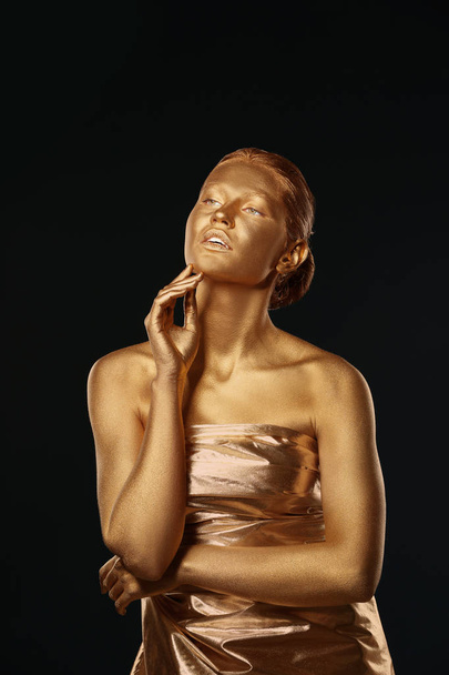 Portrait of beautiful lady with gold paint on skin against black background - Foto, Imagen