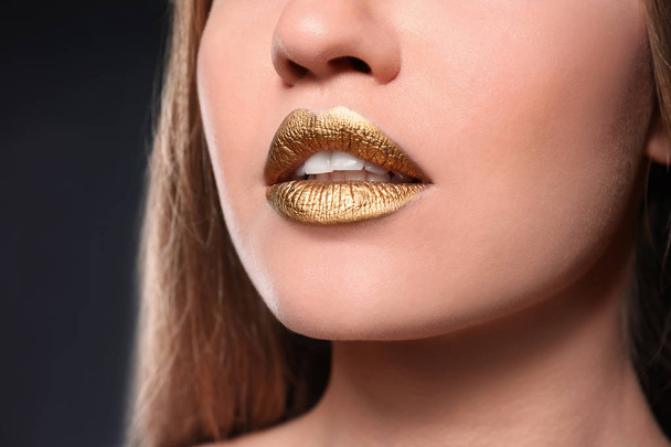 Woman with gold lipstick on grey background, closeup - Foto, Bild