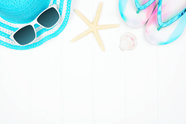 Beach accessories on a white wood background. Summer vacation concept frame with copy space. Sunglasses, sea shells, flip flops and blue striped hat. - Photo, Image