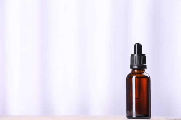Bottle of essential oil on light background, space for text. Cosmetic product - Foto, afbeelding
