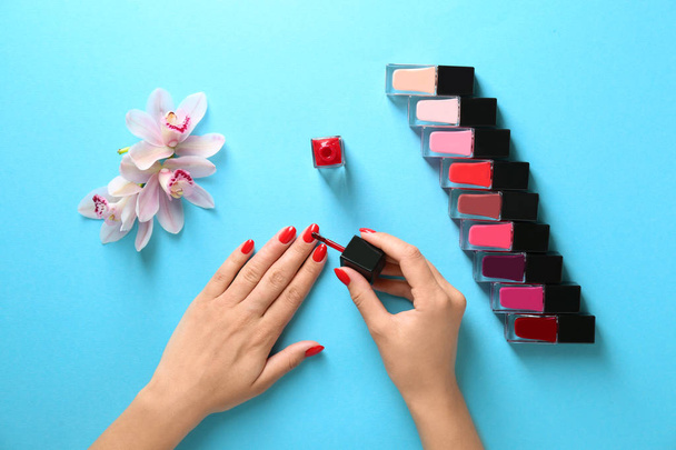 Woman applying bright nail polish on color background, top view - Foto, imagen