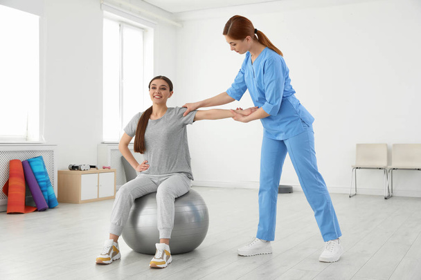Professional physiotherapist working with female patient in rehabilitation center - Foto, afbeelding