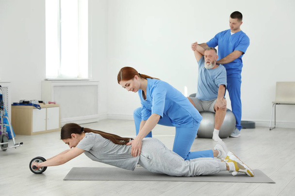 Professional physiotherapists working with patients in rehabilitation center - Foto, afbeelding