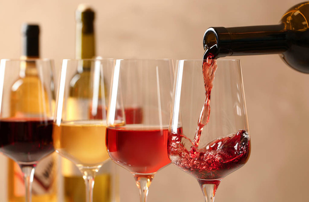 Pouring wine from bottle into glass on blurred background, closeup - Photo, image