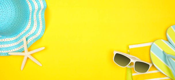 Acessórios de praia em um fundo amarelo. Banner conceito de férias de verão com espaço de cópia. Óculos de sol, conchas do mar, toalha, chinelos e chapéu listrado azul
. - Foto, Imagem