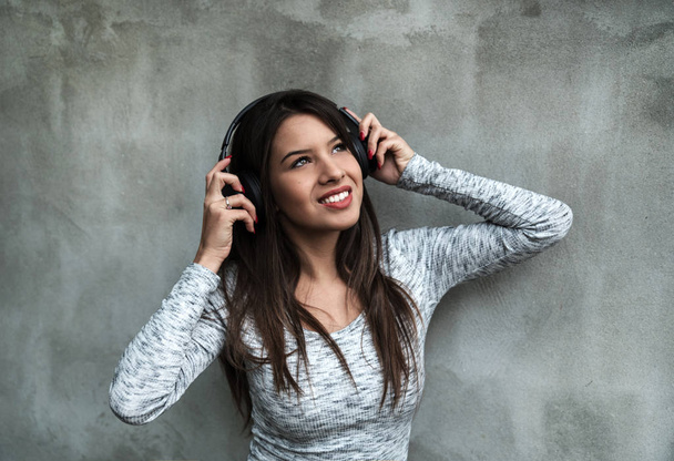 Νεαρή όμορφη γυναίκα με ακουστικά θέτουν  - Φωτογραφία, εικόνα