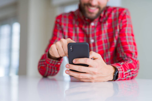 Az ember kezét használ smartphone és mosolyogva közelről - Fotó, kép