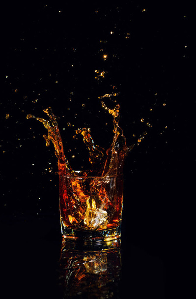 Isolated shot of whiskey with splash on black background - Foto, immagini