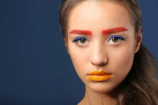 Young woman with dyed eyebrows and creative makeup on dark background - Photo, Image