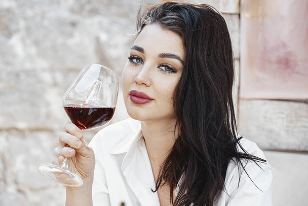 Young beautiful woman drinking red wine at street cafe in European town. - Фото, зображення