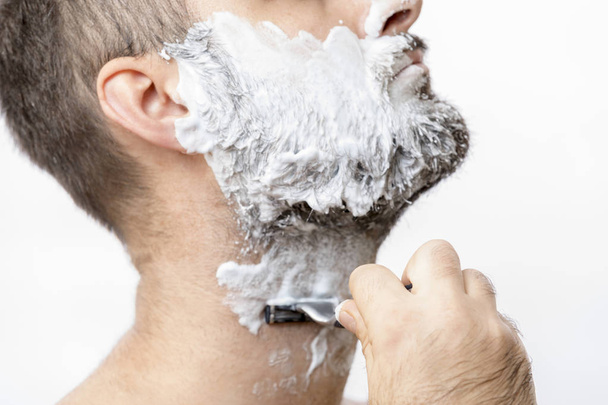 Man shaves his beard with a razor - 写真・画像