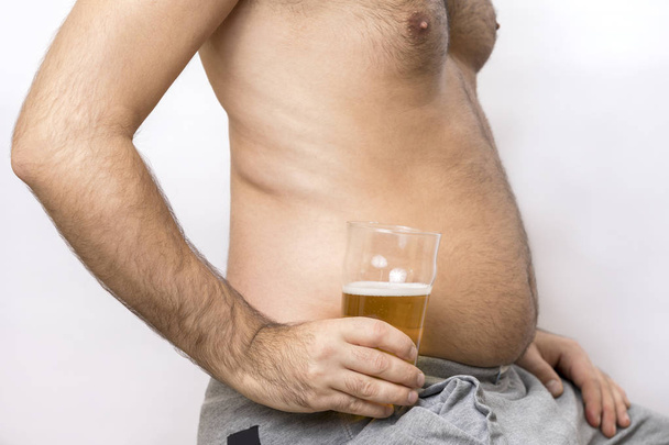 Mann mit dickem Bauch hält ein Glas Bier in der Hand - Foto, Bild