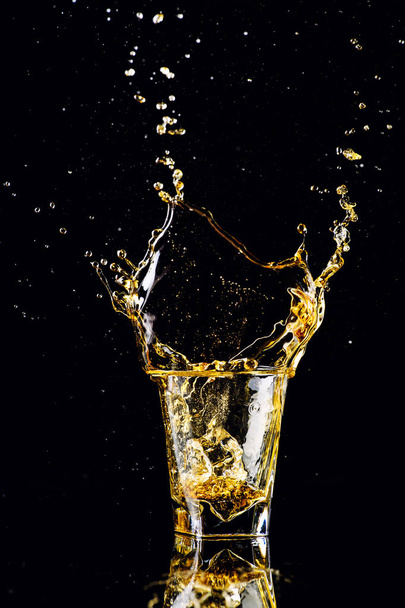 Isolated shot of whiskey with splash on black background, brandy - Foto, Imagen
