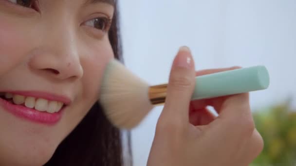 Asian woman using powder by brush make up in front mirror, Happy female using beauty cosmetics to improve herself ready to working in bedroom at home. Lifestyle women at home concept. Slow motion shot - Footage, Video