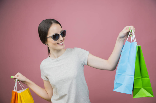 piękna dziewczyna ubrana w okulary przeciwsłoneczne gospodarstwa torby na zakupy  - Zdjęcie, obraz