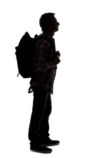 Silhouette of a male tour guide hiking and carrying a backpack on a white background.  The isolated side view man can be used for composites.  Depicts adventure and exploration.  - Fotó, kép