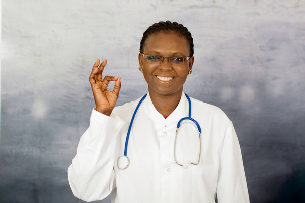 Vriendelijke vrouwelijke arts met oke teken - Foto, afbeelding