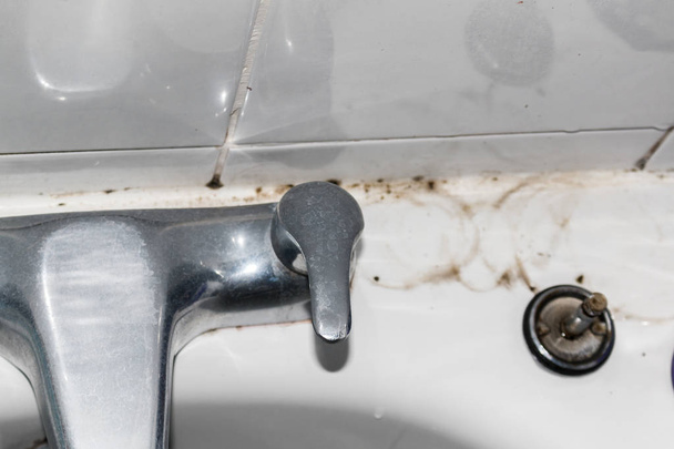 Saleté et moisissure de salle de bains sur le jointoiement et les carreaux derrière les robinets
 - Photo, image