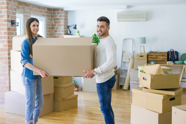 Красивая молодая пара переезжает в новый дом, держит большую картонную коробку
 - Фото, изображение