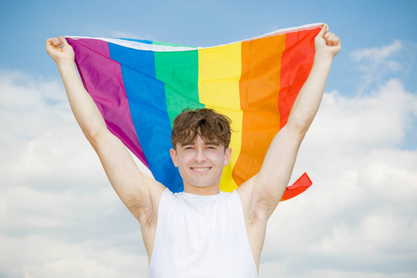 Caucasian male on a beach holding a Pride flag - Фото, зображення