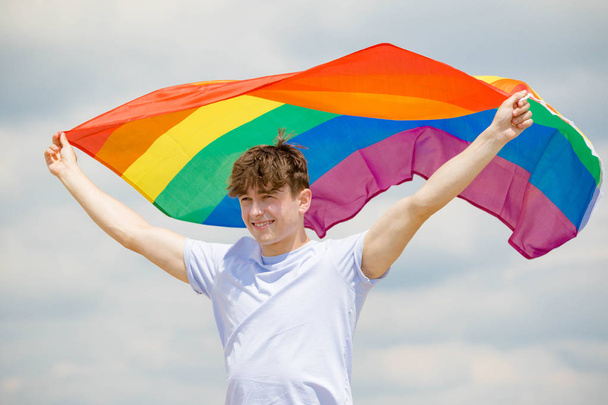 Caucasian male on a beach holding a Pride flag - Фото, зображення
