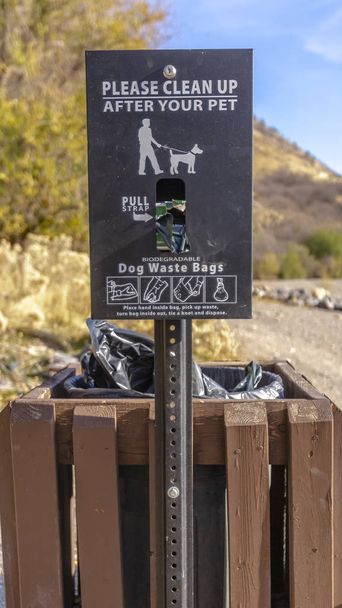 vertikaler Hundekotkorb mit einem Schild mit der Aufschrift "Bitte aufräumen" - Foto, Bild
