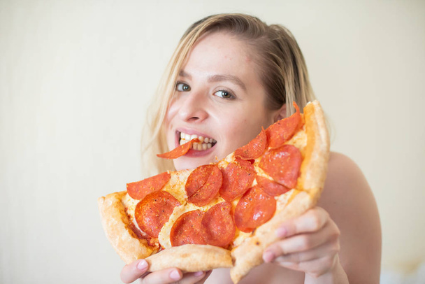 European girl with short hair posing with pieces of delicious pizza. - Фото, зображення