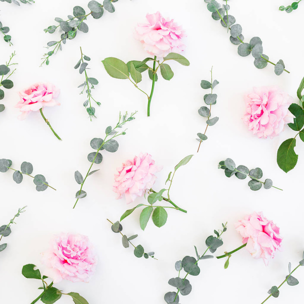 Bloemmotief van roze rozen bloemen en eucalyptus op wit. Platte lay, bovenaanzicht. - Foto, afbeelding