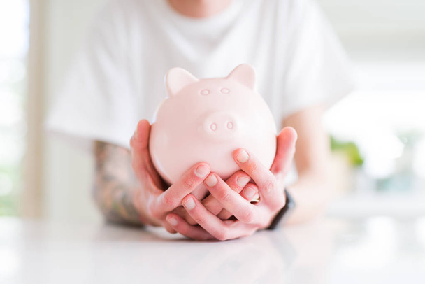 Close-up de homem segurando porquinho banco, economizando dinheiro para o investimento
 - Foto, Imagem
