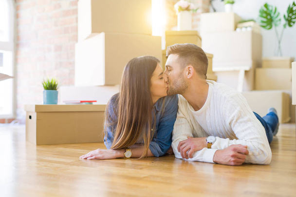 Joven hermosa pareja tumbada en el suelo de la nueva casa, sonriendo en el amor muy feliz por mudarse a un nuevo apartamento
 - Foto, Imagen