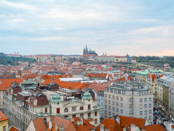 Prague, Czech republic - april 2019: Vintage town from birds view. St. Vitus Cathedral on horizon, orange roofs of buildings. Colourful ancient architecture. Cloudy early morning in Prague. - Φωτογραφία, εικόνα