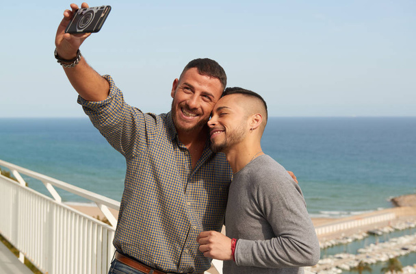 люди, гомосексуальность, однополые браки и концепция любви - Портрет счастливой гей-пары на открытом воздухе, делающей селфи с помощью мобильного телефона
 - Фото, изображение