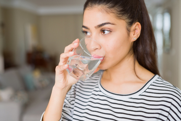 Όμορφη νεαρή γυναίκα πίνοντας ένα φρέσκο ποτήρι νερό στο σπίτι - Φωτογραφία, εικόνα