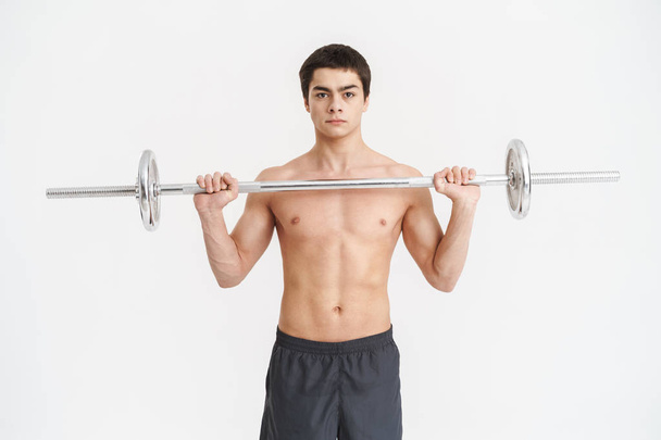 Confident fit young shirtless sportsman doing exercises - Photo, image