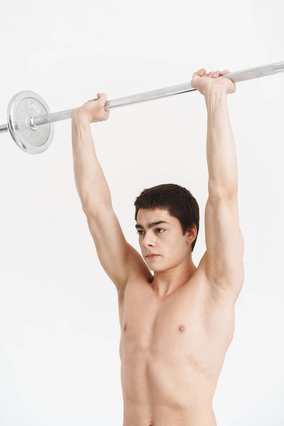 Confident fit young shirtless sportsman doing exercises - 写真・画像