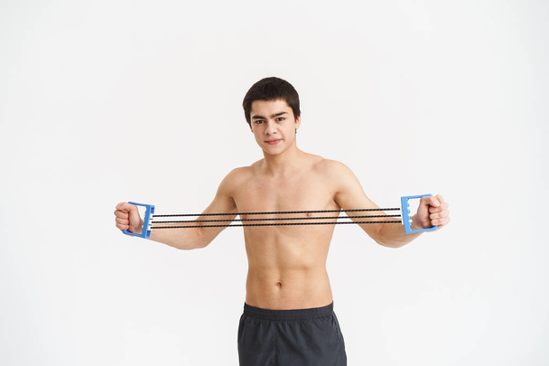 Confident fit young shirtless sportsman doing exercises - 写真・画像