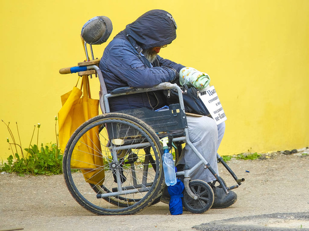 Borovsk, Russia - May, 25, 2019: image of a beggar in a wheelchair near the walls of a monastery in Borovsk, Russia - Valokuva, kuva