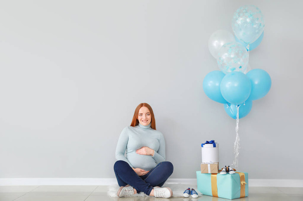 Beautiful pregnant woman with baby shower gifts near light wall - Foto, afbeelding