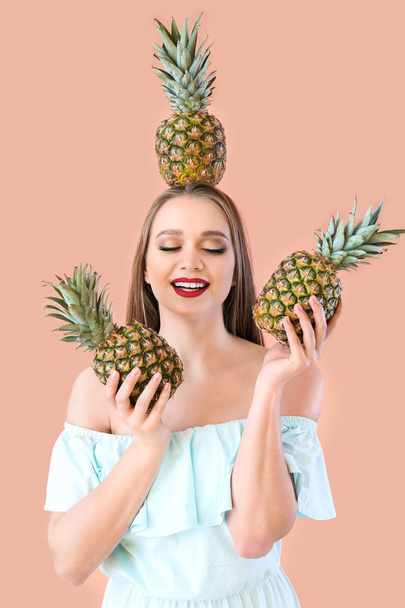 Mooie jonge vrouw met ananassen op kleur achtergrond - Foto, afbeelding