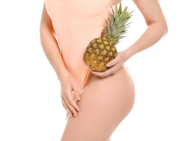 schöne junge Frau im Badeanzug und mit Ananas auf weißem Hintergrund - Foto, Bild