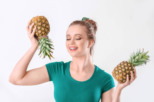 Beautiful young woman with pineapples on white background - Foto, afbeelding