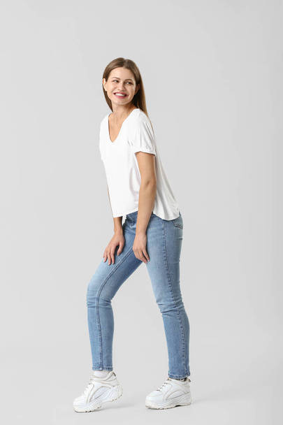 Beautiful young woman in jeans on white background - 写真・画像