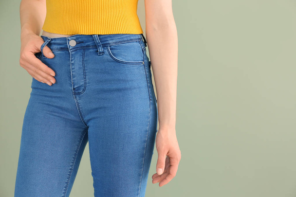 Молода жінка в стильних джинсових штанях на кольоровому фоні
 - Фото, зображення